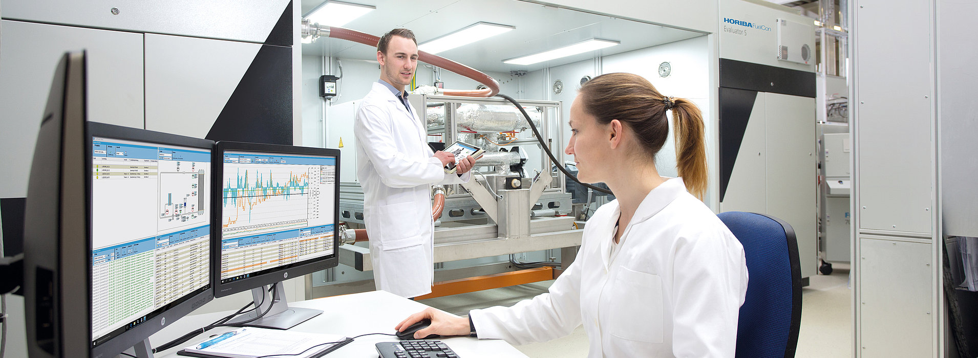 Zwei Mitarbeiter prüfen Testdaten an einem Teststand für PEM-Brennstoffzellensysteme